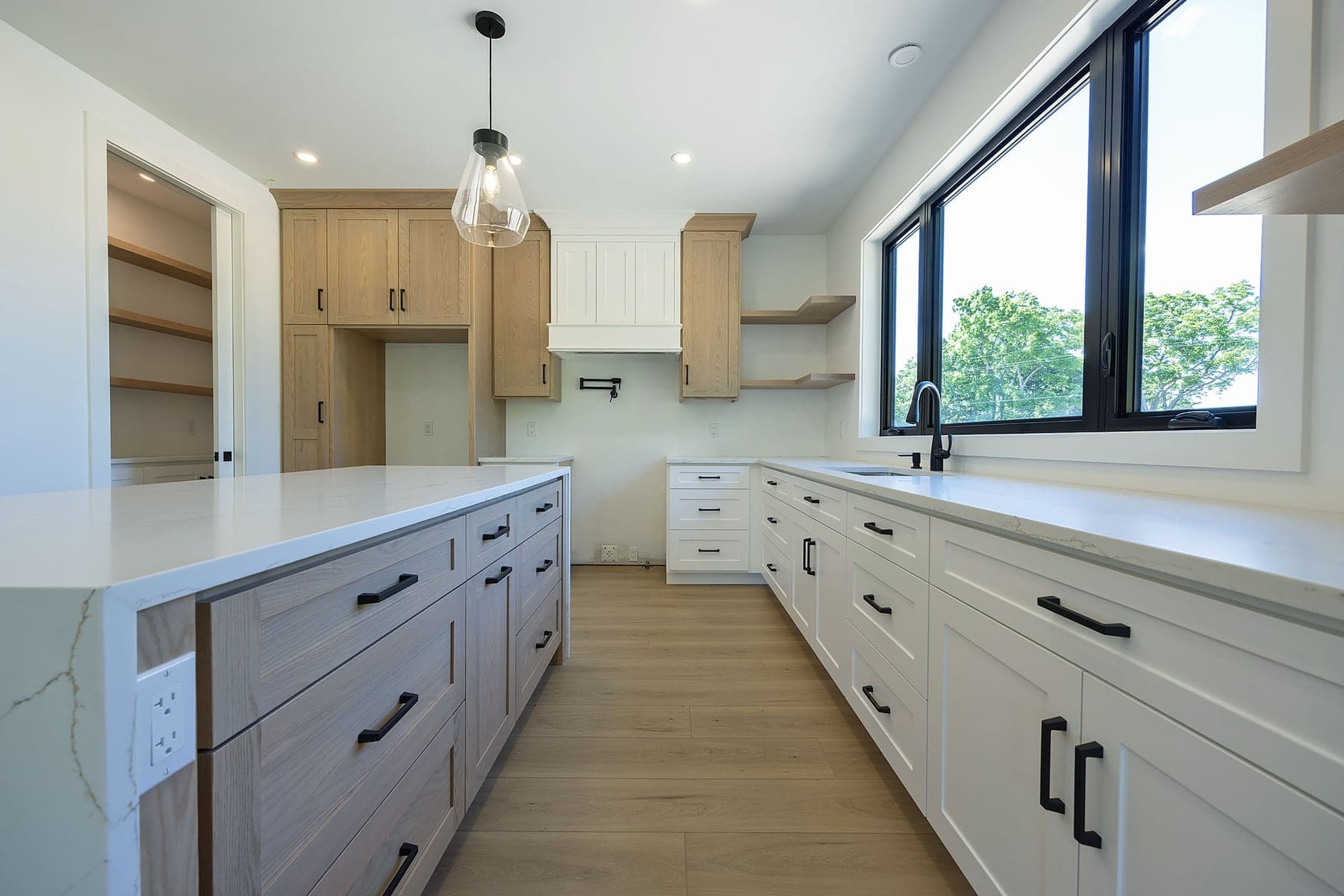 White oak and quartz kitchen in a completed SBR home, looking out over the rear yard